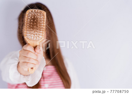 Closeup hand holding comb and hair fall problem isolated grey background. Closeup hand holding comb and hair fall problem isolated grey background. 77708750