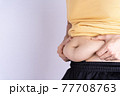 Fat man holding excessive fat belly isolated grey background. 77708763
