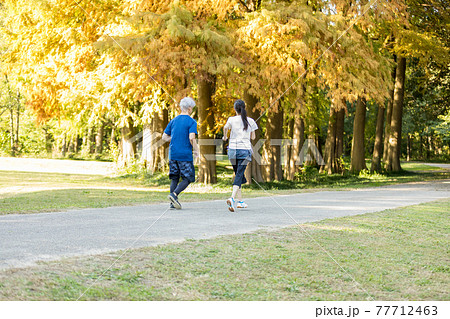 紅葉する公園をの中を走るシニア夫婦 紅葉する公園をの中を走るシニア夫婦 77712463