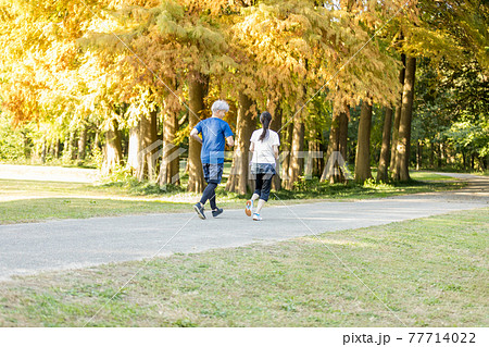 紅葉する公園をの中を走るシニア夫婦 紅葉する公園をの中を走るシニア夫婦 77714022