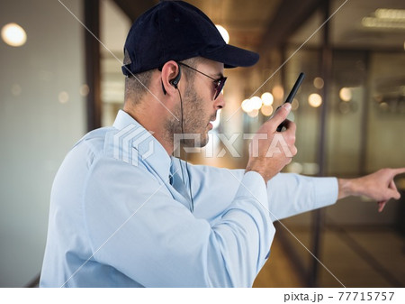 Composition of male security guard using walkie talkie holding hand out over blurred background Composition of male security guard using walkie talkie holding hand out over blurred background 77715757