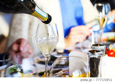 The waiter pours white wine into a glass. Banquet, cutlery, table setting. The waiter pours white wine into a glass. Banquet, cutlery, table setting. 77715851