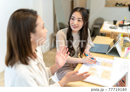 住宅の間取り図面を見ながら打ち合わせをする女性二人　ビジネスシーン 77719180