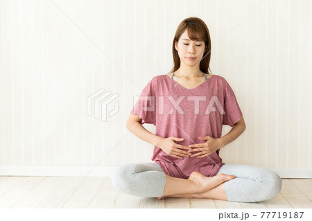 女性は座って瞑想している。 女性は座って瞑想している。 77719187