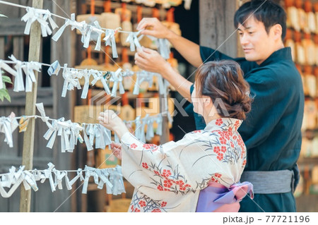 おみくじを結ぶ浴衣姿の男女 77721196