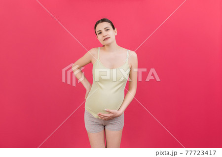 Pregnant woman with a pain in her back on colored Background isolated Pregnant woman with a pain in her back on colored Background isolated 77723417