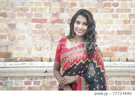 Portrait of a smiling beautiful Indian woman wearing red saree. Portrait of a smiling beautiful Indian woman wearing red saree. 77724890