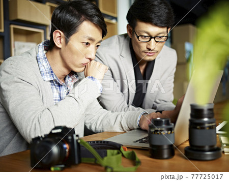 two asian photographers looking at laptop computer with serious facial expression two asian photographers looking at laptop computer with serious facial expression 77725017