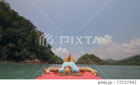 Seductive woman lifts up long legs lying on canoe on sea Seductive woman lifts up long legs lying on canoe on sea 77727442