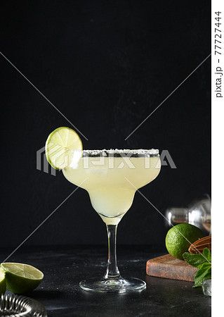 Classic Margarita cocktail with lime and ice cube on black background. Freshness summer alcoholic beverage. 77727444