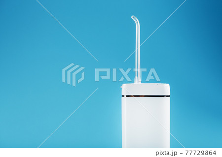 White oral irrigator on a blue background. White oral irrigator on a blue background. 77729864