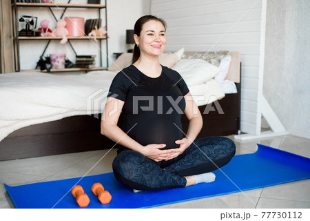 Pregnant woman exercing yoga at home. Pregnancy yoga and fitness. Pregnant woman exercing yoga at home. Pregnancy yoga and fitness. 77730112