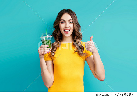 Pretty woman with tasty green detox juice on blue background Pretty woman with tasty green detox juice on blue background 77730697