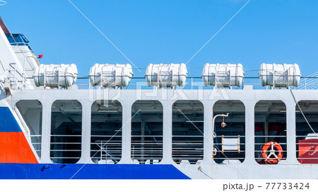 A group of inflatable liferafts arranged in a row on the upper deck of a cruise ship. 77733424