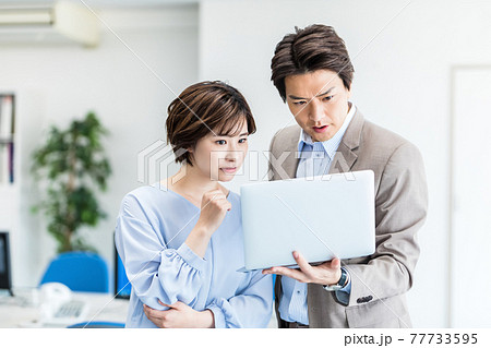 パソコンを見ながら打ち合わせする若い男女 77733595