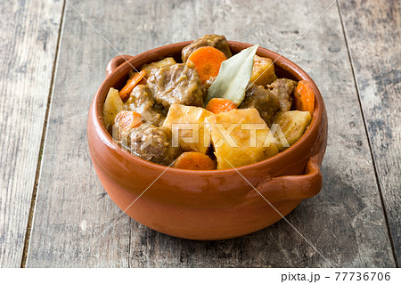 Beef meat stewed with potatoes, carrots and spices in ceramic pot on wooden table Beef meat stewed with potatoes, carrots and spices in ceramic pot on wooden table 77736706