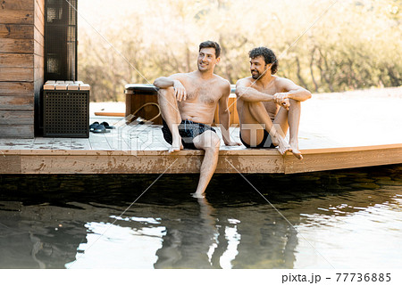 Company of male friends sitting on the terrace and wetting their feet 77736885