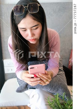 Young beautiful woman playing smart phone in the cafe 77737287