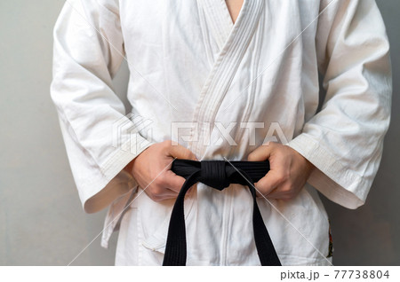 A man in kimono is holdong his black belt 77738804