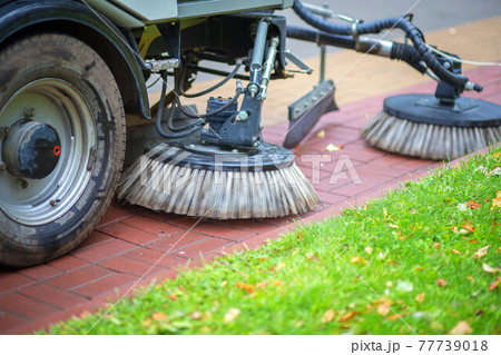 a street sweeper drives through the park and sweeps a path from leaves and debris 77739018