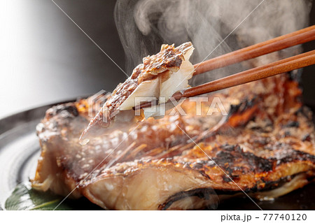 焼きたての魚を箸で摘むシーン 77740120