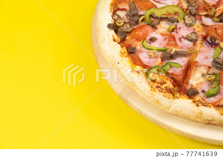 Delicious large pizza with veal and mushrooms on a yellow background Delicious large pizza with veal and mushrooms on a yellow background 77741639