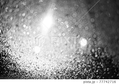 Raindrops on the glass at night. The lanterns are shining. Black and white bokeh. Car glass. Defocus. 77742716