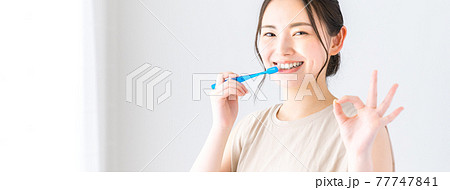 歯ブラシをしながらOKマークする若い女性 77747841