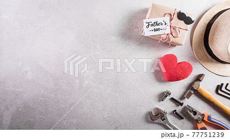 Happy Father's Day decoration including; beautiful tie with mustache, hand tools, gift box , red heart and hat on dark stone background. Happy Father's Day decoration including; beautiful tie with mustache, hand tools, gift box , red heart and hat on dark stone background. 77751239