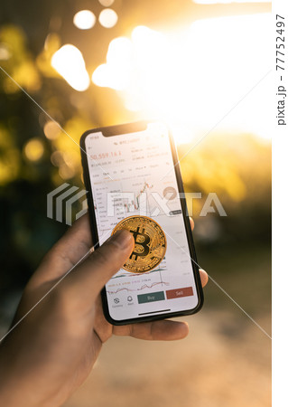 Bitcoin and charts in smartphone In hand 77752497