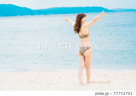 ビーチでリラックスする水着姿の女性の写真素材