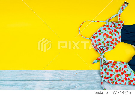 Top view of the swimsuit lying on a blue wooden and yellow background.Summer vacation concept 77754215