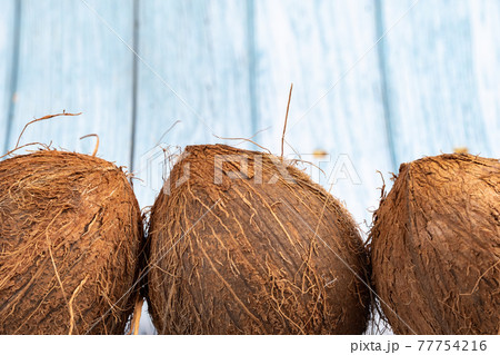 Whole coconuts on a blue wooden background.three shaggy coconuts lie on an isolated background 77754216
