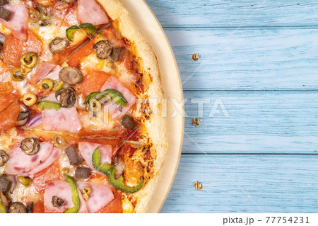 Delicious large pizza with veal and mushrooms on a blue wooden background Delicious large pizza with veal and mushrooms on a blue wooden background 77754231