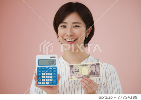 電卓と五千円札を持つ女性 77754389