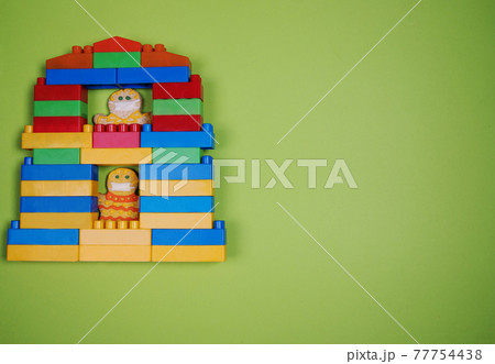 A toy house made from a construction kit with gingerbread man residents quarantined during the coronavirus pandemic. The concept of compliance with the mask mode. Copy space 77754438