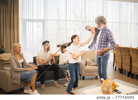 Grandfather dancing with granddaughter in front of smiling parents 77756095
