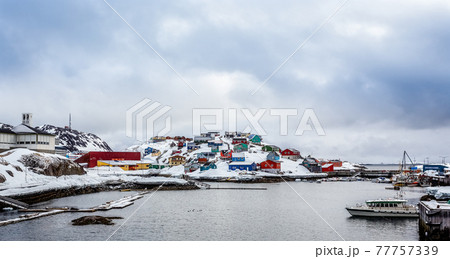 Port with boats and colorful Inuit houses on the rocks in backgr Port with boats and colorful Inuit houses on the rocks in backgr 77757339