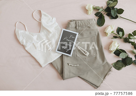 Overhead view of woman's casual spring summer outfit. Jeans, sandals, accessories and flowers on beige background. Flat lay, top view. Overhead view of woman's casual spring summer outfit. Jeans, sandals, accessories and flowers on beige background. Flat lay, top view. 77757586