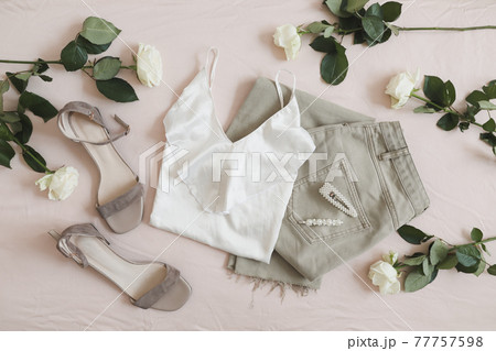 Overhead view of woman's casual spring summer outfit. Jeans, sandals, accessories and flowers on beige background. Flat lay, top view. Overhead view of woman's casual spring summer outfit. Jeans, sandals, accessories and flowers on beige background. Flat lay, top view. 77757598