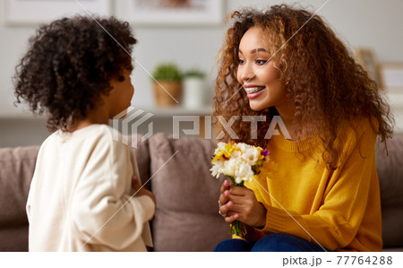 Cute little son giving flower bouquet his mom for Mothers day 77764288