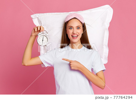 Excited female demonstrating alarm clock 77764294