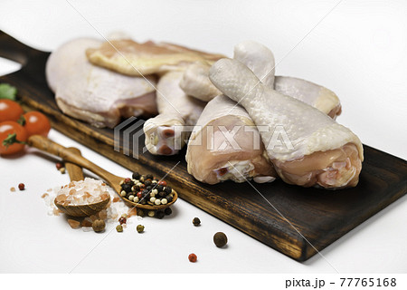 Fresh raw chicken thighs with ingredients for cooking on a wooden cutting board on white background 77765168