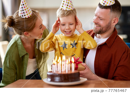 Portrait of happy child boy celebrating birthday with young parents at home 77765467