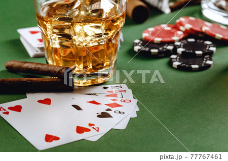 Glass of whiskey, cigar, playing cards and chips on green background 77767461