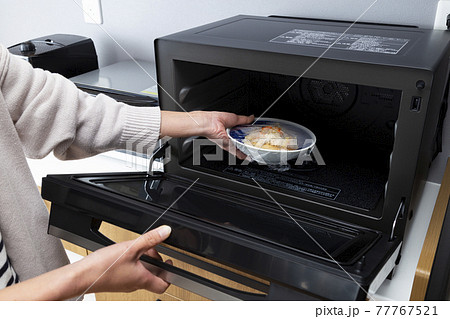 電子レンジで食事を温める女性の手元 電子レンジで食事を温める女性の手元 77767521