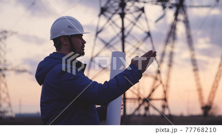 An electrician at a high voltage power plant works with a project at sunset in the sky, electrical energy design, industry concept, modern business technology, an engineer in the glare of the sun An electrician at a high voltage power plant works with a project at sunset in the sky, electrical energy design, industry concept, modern business technology, an engineer in the glare of the sun 77768210