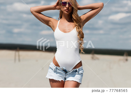Sexy woman in white swimsuit holding shirts 77768565