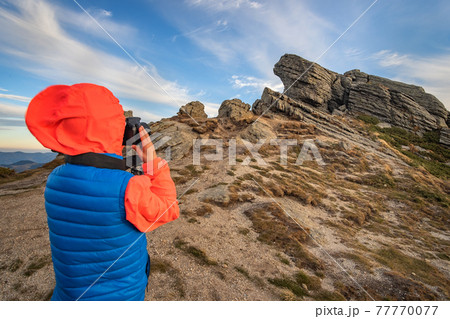 Young child boy hiker taking pictures in mountains enjoying view of amazing mountain landscape. 77770077