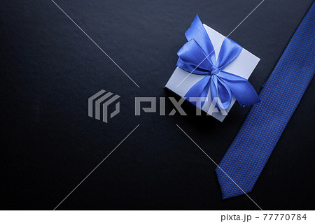 Gift dad. Blue bowtie or tie, white box with bow ribbon on dark background. Happy loving family and Fathers Day concept. Gift dad. Blue bowtie or tie, white box with bow ribbon on dark background. Happy loving family and Fathers Day concept. 77770784